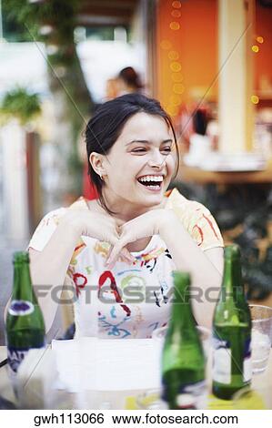 Young woman seated at a table in a restaurant and smiling View Large Photo Image Stock Photograph - Young woman seated at a table in a restaurant and smiling . Fotosearch