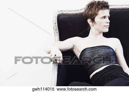 Stock Photography - Close-up of a mid adult woman sitting on a couch and looking sideways. Fotosearch