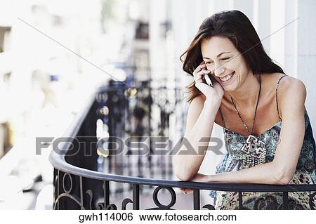 Close-up of a young woman talking on a mobile phone in the balcony View Large Photo Image Stock Photograph - Close-up of a young woman talking on a mobile phone in the balcony. Fotosearch
