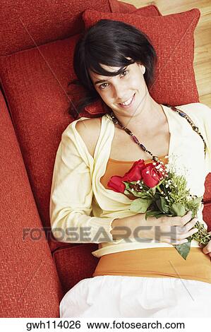 High angle view of a young woman lying on a couch and holding a bunch of flowers View Large Photo Image Stock Photograph - High angle view of a young woman lying on a couch and holding a bunch of flowers. Fotosearch