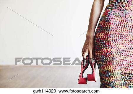 Mid section view of a woman holding a pair of shoes View Large Photo Image Stock Image - Mid section view of a woman holding a pair of shoes. Fotosearch