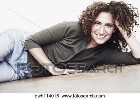 Stock Photograph - Portrait of a mid adult woman lying on the floor. Fotosearch