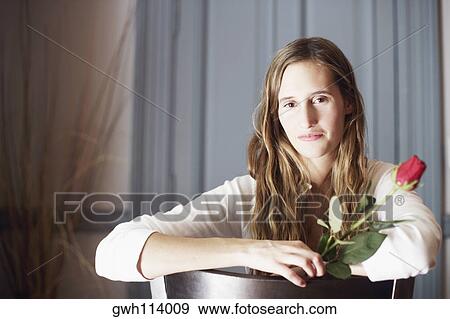 Portrait of a young woman holding a rose View Large Photo Image Stock Photo - Portrait of a young woman holding a rose. Fotosearch