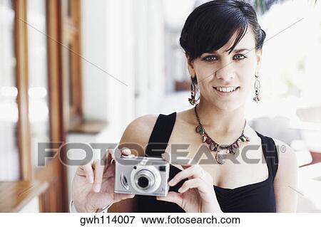 Portrait of a young woman holding a digital camera View Large Photo Image Stock Photo - Portrait of a young woman holding a digital camera. Fotosearch
