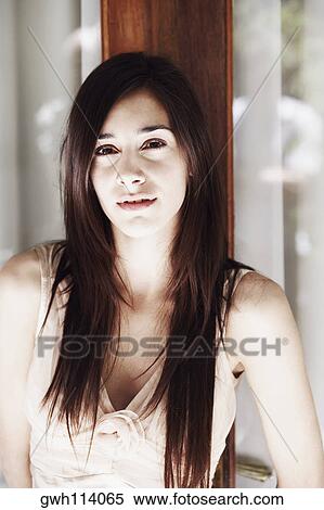 Stock Photography - Portrait of a young woman leaning against a door. Fotosearch