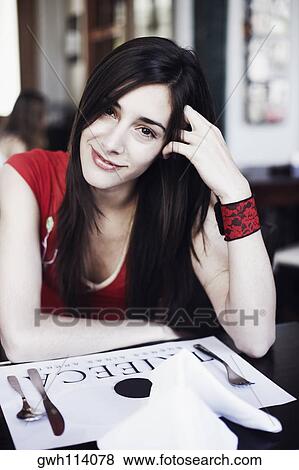 Portrait of a young woman sitting in a restaurant and smiling View Large Photo Image Stock Photo - Portrait of a young woman sitting in a restaurant and smiling . Fotosearch