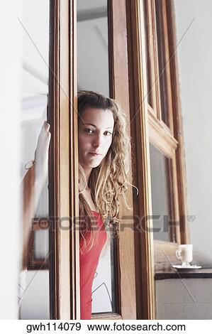Portrait of a young woman standing at a door View Large Photo Image Stock Photo - Portrait of a young woman standing at a door. Fotosearch