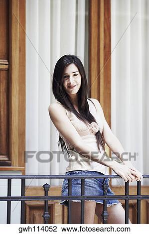 Portrait of a young woman standing in the balcony and smiling View Large Photo Image Stock Image - Portrait of a young woman standing in the balcony and smiling . Fotosearch