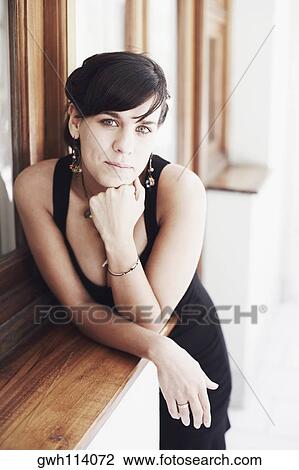 Portrait of a young woman standing with her hand on her chin View Large Photo Image Stock Image - Portrait of a young woman standing with her hand on her chin. Fotosearch