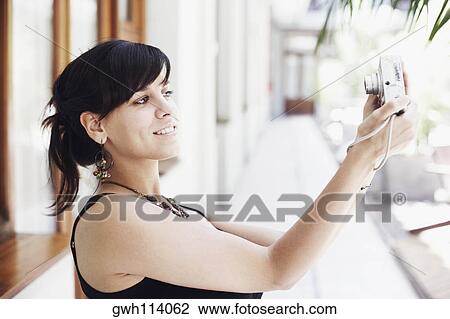 Side profile of a young woman taking a photograph of herself View Large Photo Image Stock Image - Side profile of a young woman taking a photograph of herself. Fotosearch