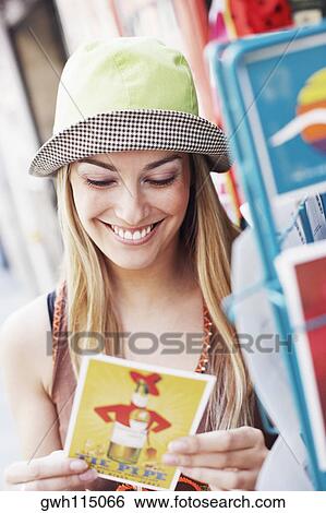 Stock Photograph - Close-up of a young woman looking at a postcard. Fotosearch