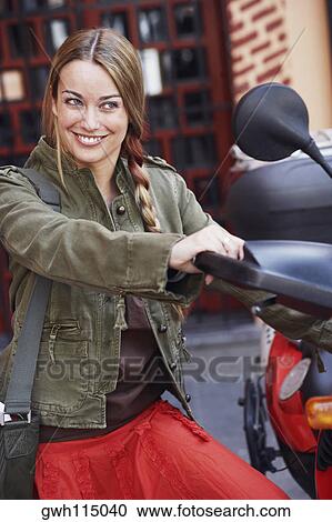 Close-up of a young woman looking at the rear-view mirror of a scooter View Large Photo Image Stock Image - Close-up of a young woman looking at the rear-view mirror of a scooter . Fotosearch