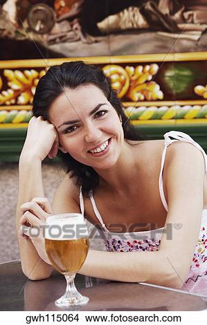 Portrait of a mid adult woman with a glass of beer in front of her View Large Photo Image Picture - Portrait of a mid adult woman with a glass of beer in front of her . Fotosearch