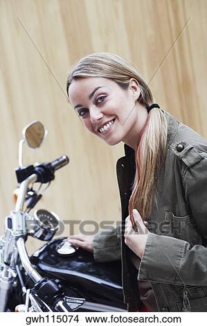Portrait of a young woman beside a motorcycle View Large Photo Image Picture - Portrait of a young woman beside a motorcycle. Fotosearch