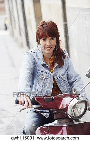 Portrait of a young woman sitting on a motor scooter and smiling View Large Photo Image Stock Image - Portrait of a young woman sitting on a motor scooter and smiling . Fotosearch