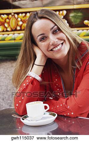 Stock Photo - Portrait of a young woman sitting with her hand in her hair. Fotosearch