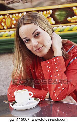 Stock Photo - Portrait of a young woman sitting with her hand in her hair. Fotosearch