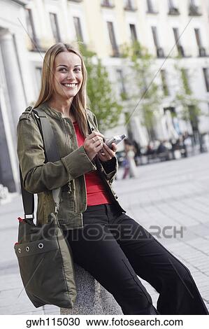 Stock Image - Portrait of a young woman using a personal data assistant . Fotosearch