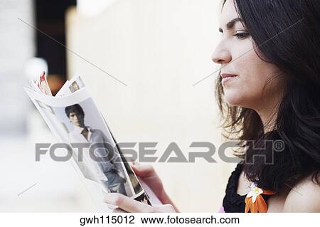 Stock Image - Side profile of a mid adult woman reading a magazine. Fotosearch