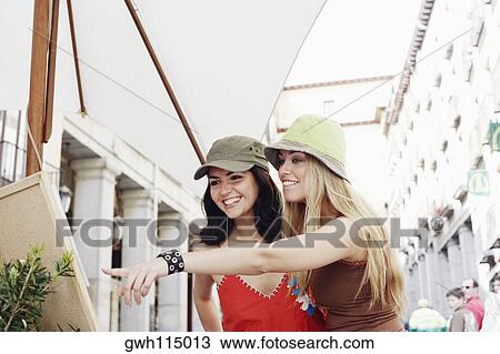 Stock Image - Young woman and a mid adult woman looking at a painting at a sidewalk cafe . Fotosearch