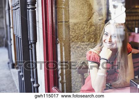Young woman sitting in a restaurant with her hand on her chin View Large Photo Image Stock Photo - Young woman sitting in a restaurant with her hand on her chin . Fotosearch