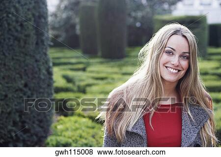 Stock Photo - Young woman smiling in a garden . Fotosearch
