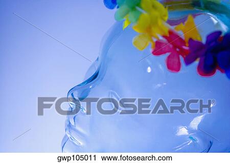 Stock Image - Close-up of a garland of artificial flowers on the head of a transparent statue. Fotosearch
