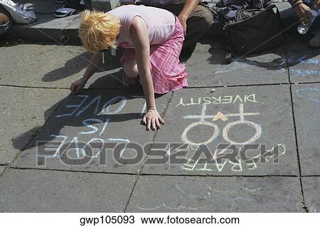 Stock Image - High angle view of a lesbian woman writing messages with a chalk on the road. Fotosearch