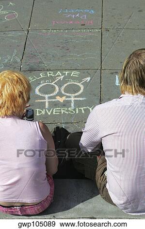 Stock Photo - High angle view of a man and a woman sitting on the street near a chalk drawing. Fotosearch