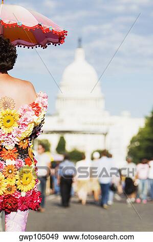 Stock Photo - Rear view of a person in a flower costume at a gay parade. Fotosearch
