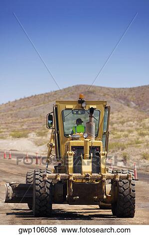 Stock Photo - Bulldozer moving on a dirt road. Fotosearch