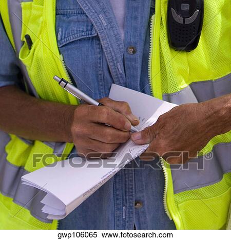 Stock Photography - Close-up of a construction worker writing on paper. Fotosearch
