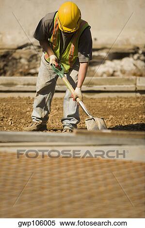 Construction worker using a shovel at a construction site View Large Photo Image Stock Photography - Construction worker using a shovel at a construction site. Fotosearch