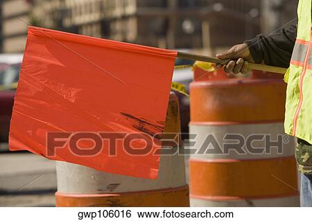 Mid section view of a man holding a red flag at a construction site View Large Photo Image Stock Photograph - Mid section view of a man holding a red flag at a construction site. Fotosearch