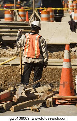 Stock Photo - Rear view of a construction worker working at a construction site. Fotosearch