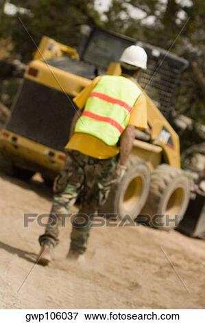 Rear view of a construction worker walking towards a bulldozer View Large Photo Image Stock Photo - Rear view of a construction worker walking towards a bulldozer. Fotosearch