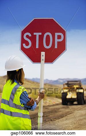 Rear view of a man holding a stop sign on a dirt road View Large Photo Image Stock Photograph - Rear view of a man holding a stop sign on a dirt road. Fotosearch