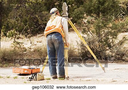 Rear view of a surveyor looking through a theodolite View Large Photo Image Stock Image - Rear view of a surveyor looking through a theodolite. Fotosearch