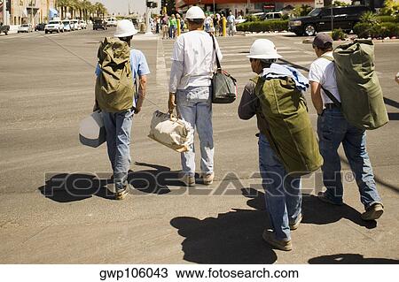 Rear view of four men crossing a road with bags View Large Photo Image Stock Image - Rear view of four men crossing a road with bags. Fotosearch