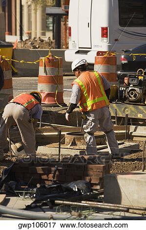 Stock Photo - Rear view of two construction workers working at a construction site. Fotosearch