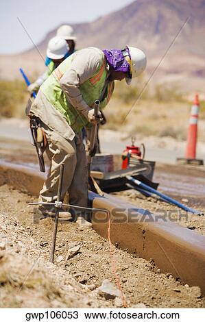 Stock Image - Three construction workers working at a construction site. Fotosearch