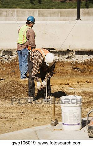 Two construction workers working at a construction site View Large Photo Image Stock Photo - Two construction workers working at a construction site. Fotosearch