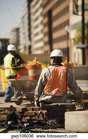 Two construction workers working at a construction site View Large Photo Image Stock Photograph - Two construction workers working at a construction site. Fotosearch
