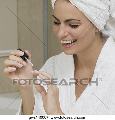 Close-up of a young woman applying nail polish on her fingernails View Large Photo Image Stock Photo - Close-up of a young woman applying nail polish on her fingernails. Fotosearch