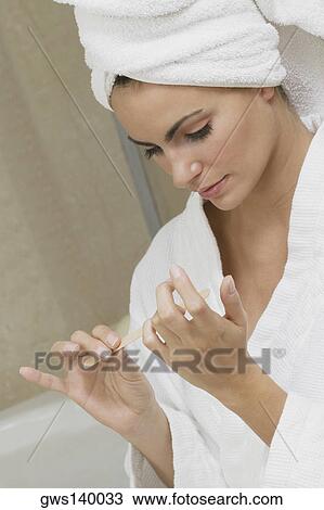 Stock Image - Close-up of a young woman filing her fingernails. Fotosearch