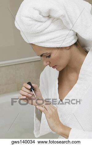 Picture - Close-up of a young woman painting her fingernails. Fotosearch