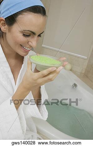 Close-up of a young woman sitting near a bathtub smelling a dish of bath crystals View Large Photo Image Stock Photo - Close-up of a young woman sitting near a bathtub smelling a dish of bath crystals. Fotosearch