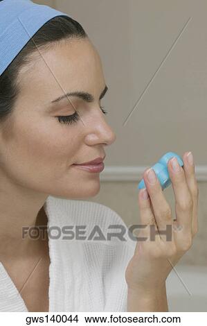 Picture - Close-up of a young woman smelling a bar of soap. Fotosearch