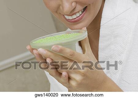 Stock Image - Close-up of a young woman smelling a dish of bath crystals. Fotosearch