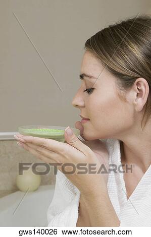 Stock Photograph - Close-up of a young woman smelling a dish of bath crystals. Fotosearch